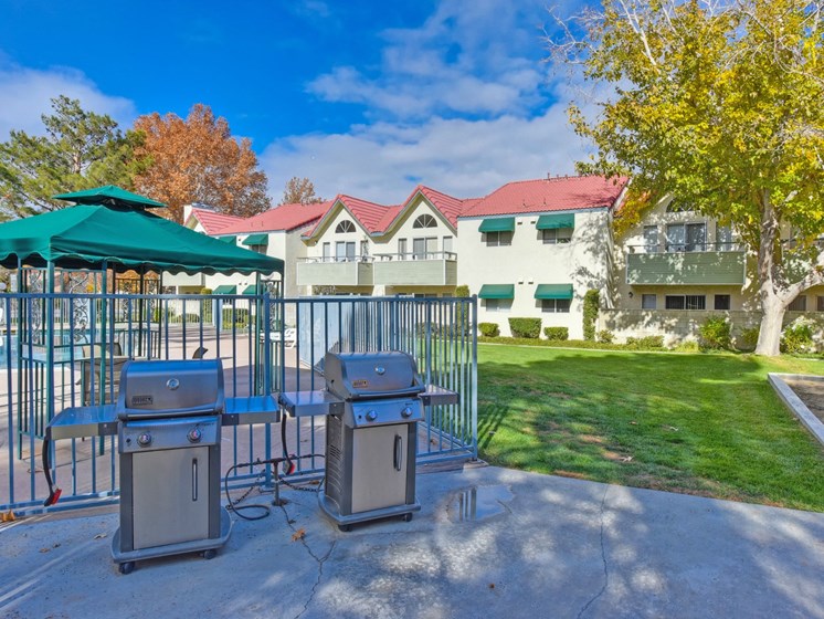 Outdoor BBQ Picnic Area with Grills, Gate, Grass and View of Pool